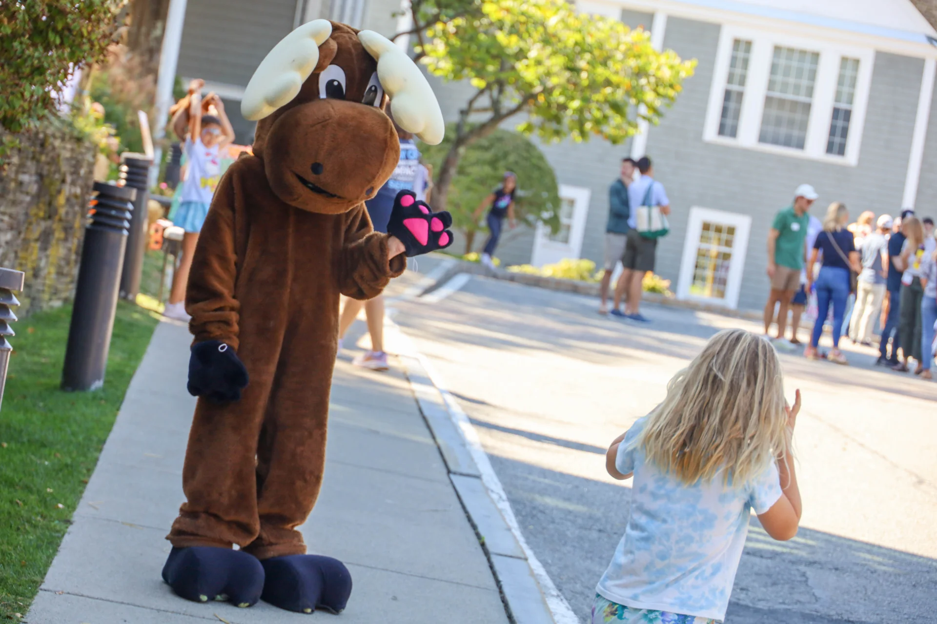 Moose mascot waving to child